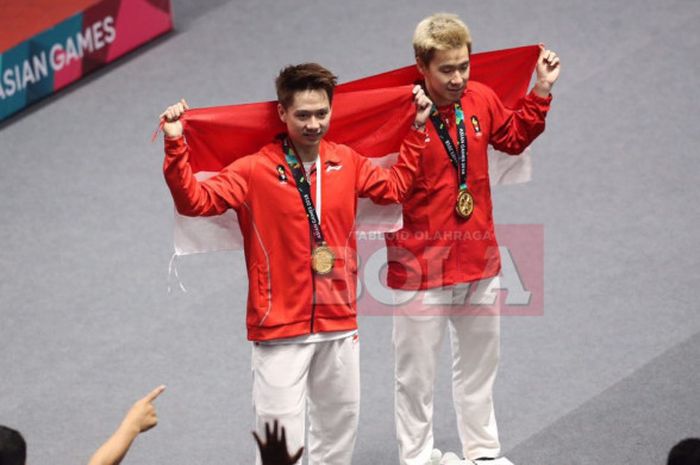    Marcus Fernaldi Gideon (kanan) dan Kevin Sanjaya Sukamuljo (kiri) membentangkan bendera Merah Putih seusai menjuarai nomor ganda putra pada Asian Games 2018.