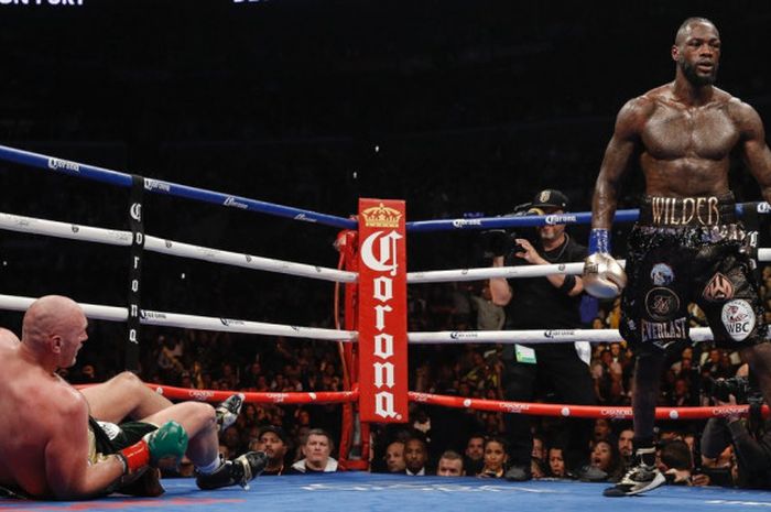 Momen saat Deontay Wilder (kanan) menjatuhkan  Tyson Fury (kiri) dalam pertarungan tinju yang digelar di Staples Center, Los Angeles, Amerika Serikat, Sabtu (1/12/2018) malam waktu setempat.