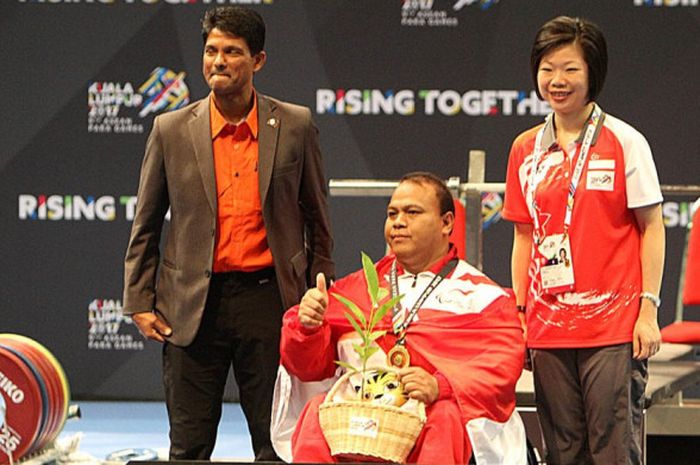 Lifter difabel Indonesia, Anto Boi, berpose di atas podium kampiun ASEAN Para Games 2017. Anto meraih medali emas pada kelas 88 kg putra setelah mengangkat beban 180 kg.