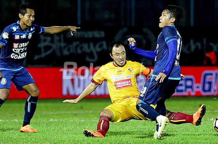 Aksi gelandang Sriwijaya FC, Yu Hyun-koo (tengah), saat melakukan tekel kepada pemain Arema FC dalam laga pekan ke-13 Liga 1 di Stadion Kanjuruhan Malang, Jawa Timur, Jumat (07/07/2017) malam.