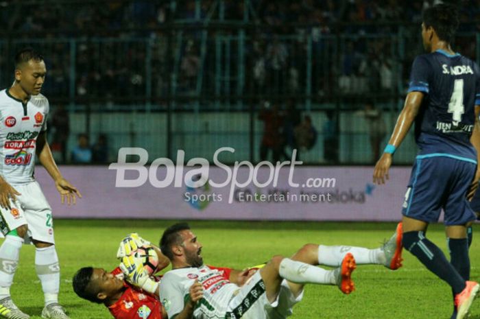 Kiper Arema FC Utam Rusdiana dan penyerang PS TNI Elio Bruno Martins terjatuh setelah terlibat duel dalam laga pekan ke-29 Liga 1 di Stadion Kanjuruhan, Malang, Sabtu (14/10/2017).