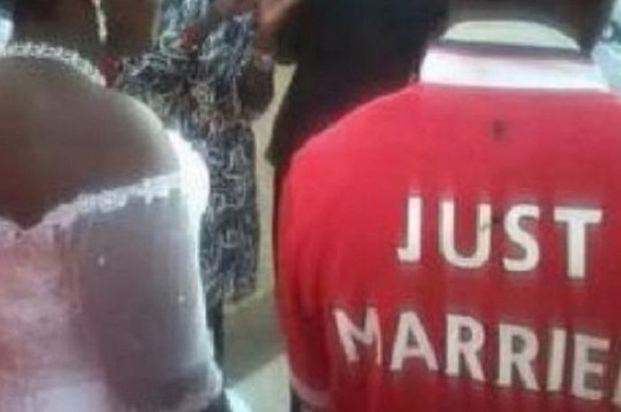 Fans Manchester United melangsungkan pernikahan dengan mengenakan kostum bertuliskan 