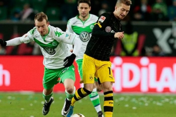 Gelandang Borussia Dortmund, Marco Reus (K), berebut bola dengan Maximilan Arnold dalam laga Bundesliga melawan Wolfsburg di Volkswagen Arena pada 5 Desember 2015.