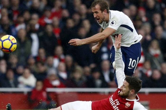 Striker Tottenham Hotspur Harry Kane melepaskan tembakan yang coba dihalangi bek Arsenal Shkodran Mustafi dalam partai Liga Inggris di Stadion Emirates, London, 18 November 2017.