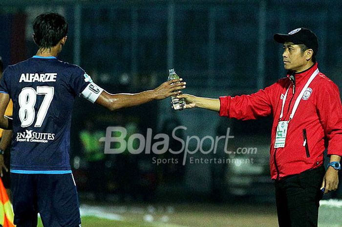 Pelatih Arema FC, Joko Susilo (kanan), memberikan air mineral kepada pemainnya, Johan Ahmat Farizi, saat timnya tampil melawan Persela Lamongan dalam laga pekan ke-24 Liga 1 di Stadion Kanjuruhan Malang, Jawa Timur, Sabtu (16/09/2017) malam.