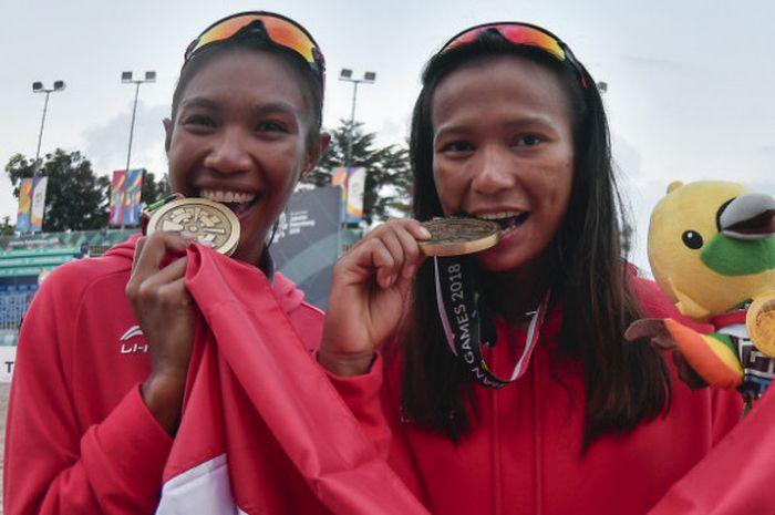 Pebola voli pantai putri Indonesia Putu Dini Jasita Utami (kanan) dan Dhita Juliana (kiri) menggigit medali perunggu yang diraih usai mengalahkan tim voli Kazakhstan pada final voli pantai putri Asian Games 2018 di arena Jakabaring Sport City, Palembang, Sumsel, Senin (27/8/2018).