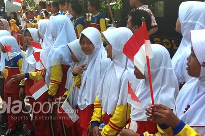 Pelajar dari SD Muhammadiyah 16 Surakarta menyambut kedatangan api obor Asian Games 2018.