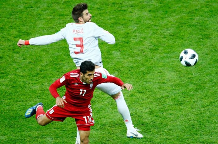 Bek Spanyol, Gerard Pique (atas), berduel dengan pemain Iran, Vahid Amiri, dalam laga Grup B Piala Dunia 2018 di Kazan Arena, Kazan, Rusia pada 20 Juni 2018.