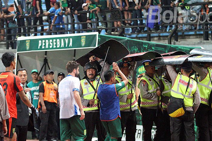 Petugas keamanan melindungi pemain dan ofisial Persebaya Surabaya dari lemparan penonton usai laga kontra Persib Bandung, Kamis (26/7/2018) di Gelora Bung Tomo Surabaya.