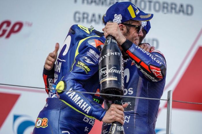       Valentino Rossi (kiri) dan Maverick Vinales (kanan) berpelukan setelah merayakan double podium yang mereka raih saat balapan MotoGP Jerman 2018, Minggu (15/7/2018).      