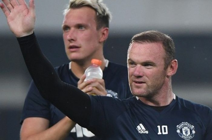 Penyerang Manchester United, Wayne Rooney, melambaikan tangan ke arah suporter saat menjalani sesi latihan di Beijing, China, pada Sabtu (23/7/2016).