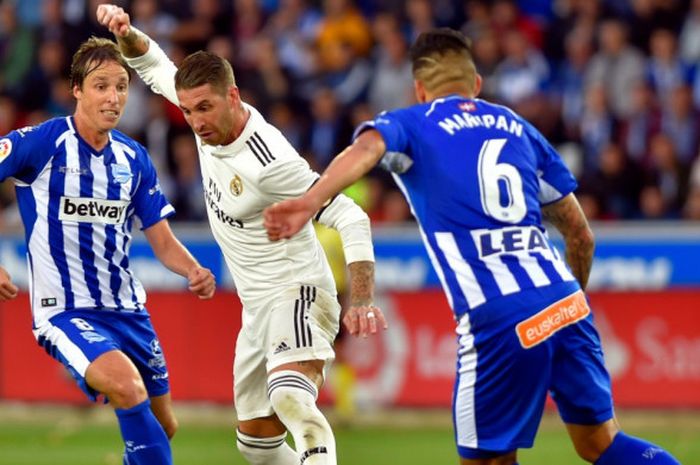 Bek Real Madrid, Sergio Ramos, berusaha lepas dari kawalan dua pemain Deportivo Alaves pada laga lanjutan Liga Spanyol di Estadio de Mendozorroza, Sabtu (7/10/2018).