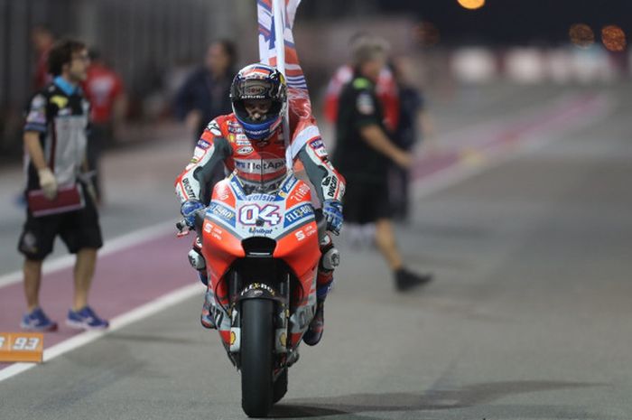 Pebalap Ducati, Andrea Dovizioso, membawa bendera nomor motornya seusai memenangi balapan seri pembuka MotoGP 2018, GP Qatar, di Sirkuit Internasional Losail, Doha, Minggu (18/3/2018).