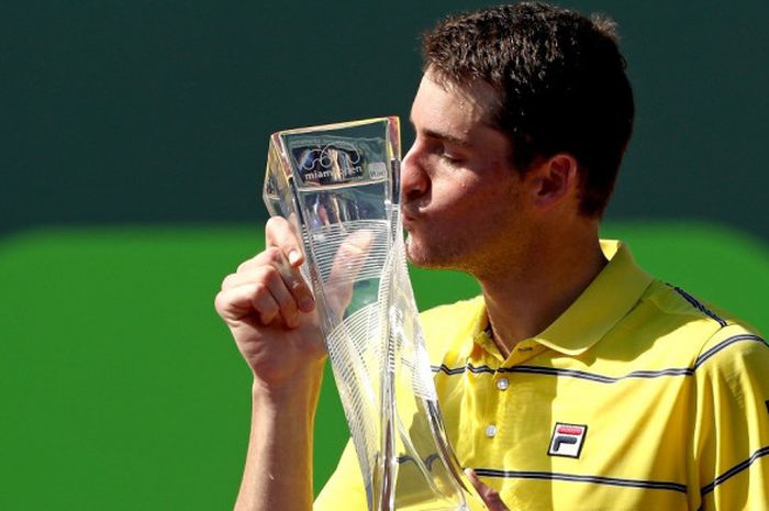 Petenis tunggal putra Amerika Serikat (AS), John Isner, mencium trofi yang diraihnya seusai menjuarai turnamen Miami Open 2018 di Crandon Park, Key Biscayne, Florida, Minggu (1/4/2018).