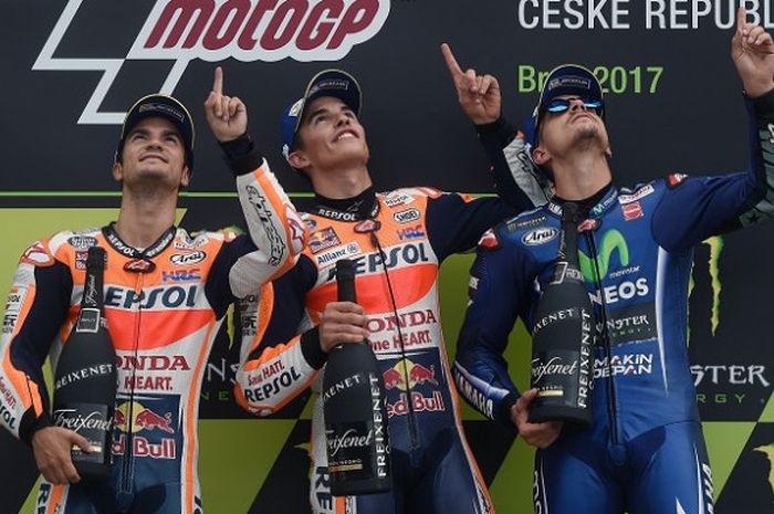 Tiga pebalap MotoGP asal Spanyol, Dani Pedrosa (kiri), Marc Marquez (tengah), dan Maverick Vinales, mengangkat jari telunjuk mereka ke arah langit untuk menghormati legenda balap motor Spanyol yang baru saja meninggal dunia, Angel Nieto, di Automotodrom, Brno, Minggu (6/8/2017).