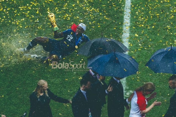 Bek Prancis, Benjamin Mendy, melakukan selebrasi dengan meluncur di lapangan sambil memegang trofi juara Piala Dunia 2018 setelah timnya menekuk Kroasia 4-2 pada laga final di Stadion Luzhniki, Moskow, 15 Juli 2018.