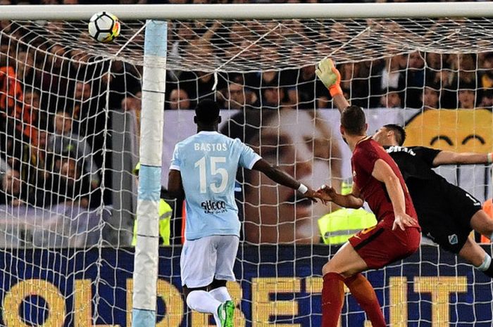 Striker AS Roma, Edin Dzeko (tengah), melihat bola hasil tandukannya yang hanya menerpa mistar gawang dalam laga Liga Italia 2017-2018 menghadapi Lazio di Stadio Olimpico, Roma, Italia, pada Minggu (15/4/2018).