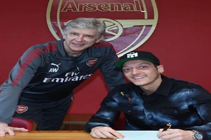 Mesut Oezil (kiri) berfoto dengan pelatih Arsenal, Arsene Wenger, setelah menandatangani kontrak baru.