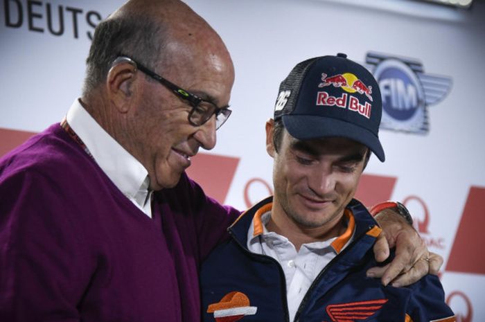 CEO Dorna Sport, Carmelo Ezpeleta (kiri), merangkul Dani Pedrosa saat sang pebalap mengumukan keputusannya untuk pensiun di Sirkuit Sachsenring, Jerman, Kamis (11/7/2018).