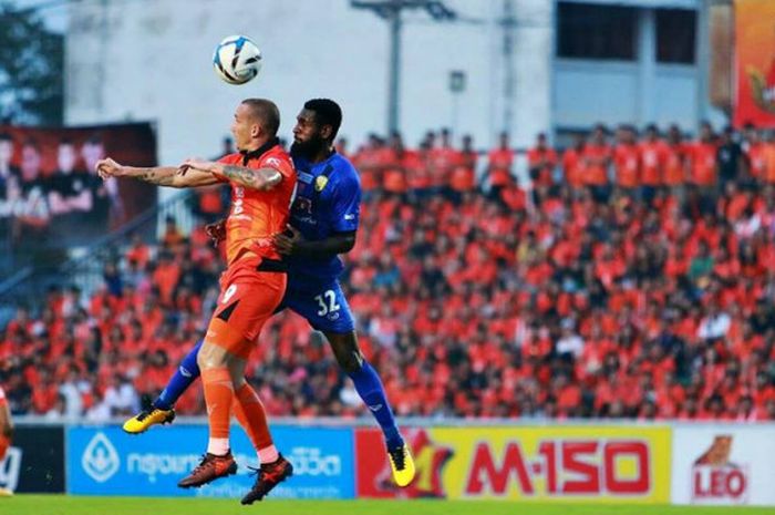  Bek asal Indonesia yang membela Khon Kaen FC, Rudolof Yanto Basna (biru) duel udara dengan striker Udon Thani FC, Miloš Stojanović pada laga Liga Thailand 2 di Stadion Udonthani, 22 April 2018.  