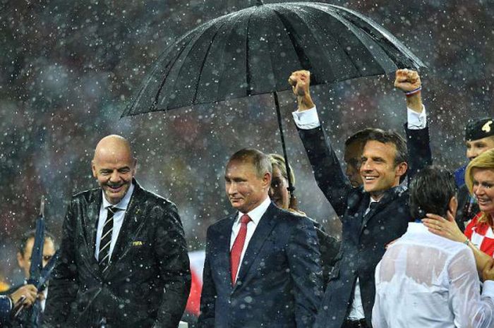 Presiden Rusia, Vladimir Putin tampak dipayungi ketika hujan deras.