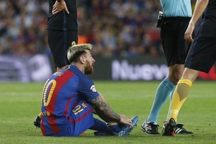 Pemain andalan FC Barcelona, Lionel Messi, duduk di lapangan lantaran mengalami cedera pada laga La Liga kontra Atletico Madrid, di Stadion Camp Nou, Rabu (21/9/2016) atau Kamis dini hari WIB. 