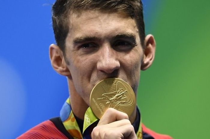 Perenang Amerika Serikat, Michael Phelps, mencium medali emas setelah turun pada nomor estafet 4x100 meter gaya bebas putra di Olympic Aquatic Stadium Minggu (7/8/2016).