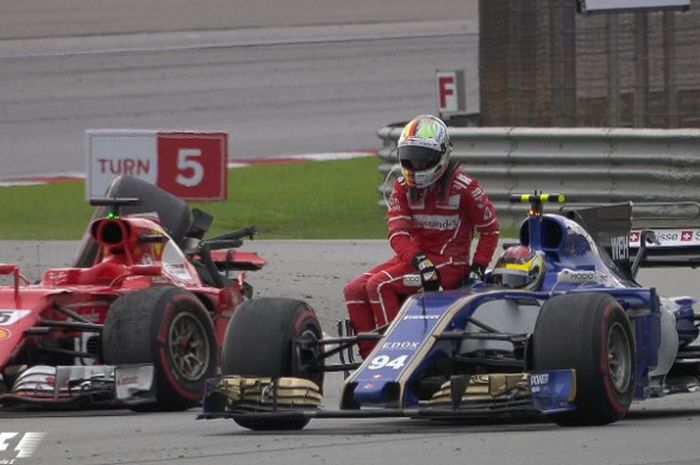 Sebastian Vettel menaiki mobil Pascal Wehlrein untuk kembali ke pit setelah mobilnya rusak akibat bersenggolan dengan Lance Stroll selepas balapan F1 GP Malaysia (1/10/2017).