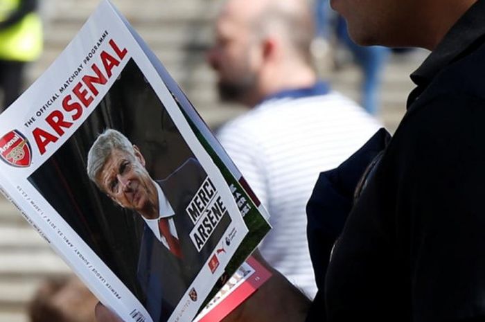 Seorang penggemar memegang majalah dengan halaman muka foto pelatih Arsenal, Arsene Wenger, di tengah laga Liga Inggris antara Arsenal lawan West Ham United di Emirates, London, 22 April 2018.