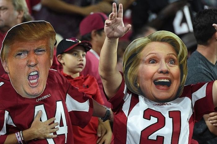 Fans dari klub futbol Amerika Serikat, Arizona Cardinal, memakai topeng Donald Trump dan Hillary Clinton