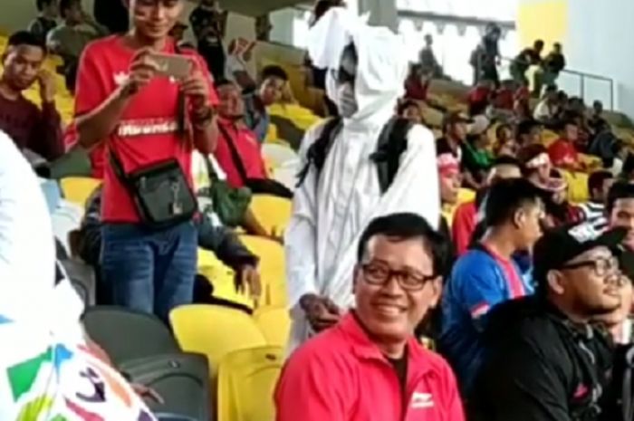 Menpora (kiri) menggunakan jaket putih mengambil gambar suporter timnas u-16 Indonesia yang menggunakan kostum pocong (kanan), Jumat (21/9/2018)