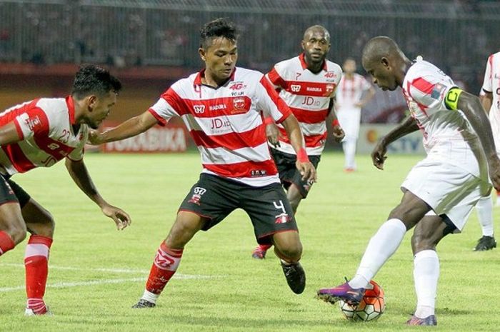 Gelandang Madura United, Asep Berlian (4), berupaya menghadagang laju kapten Persija Jakarta, Greg Nwokolo, dalam laga pekan Ke-29 Torabika Soccer Championship 2016 di Stadion Pamellengan Pamekasan, Jawa Timur (20/11/2016).