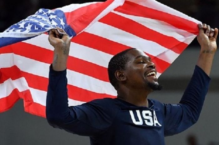 Kevin Durant mengibarkan bendera Amerika Serikat seusai meraih medali emas cabang bola basket putra, Minggu (21/8/2016). 