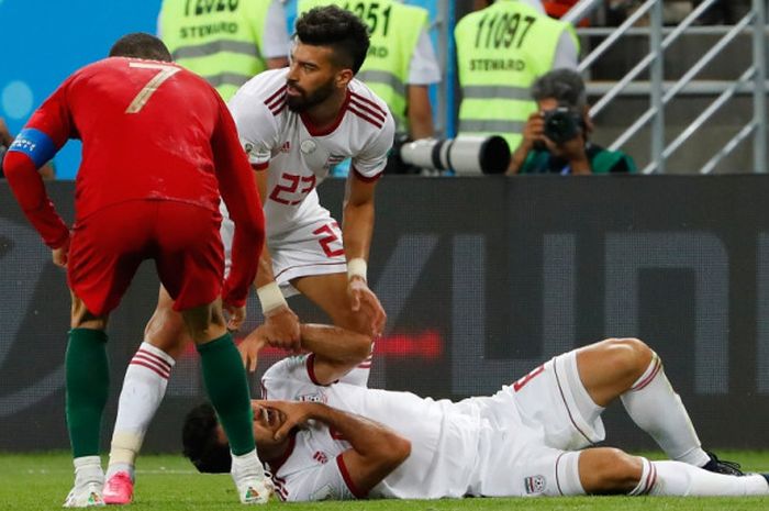 Megabintang Portugal, Cristiano Ronaldo (kiri), memeriksa kondisi bek Iran, Morteza Pouraliganji, dalam laga Grup B Piala Dunia 2018 di Mordovia Arena, Saransk, Rusia pada 25 Juni 2018.