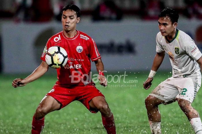 Pemain Persija Jakarta Novri Setiawan berduel dengan pemain Persebaya, Abu Rizal, di Stadion PTIK, Jakarta, Selasa (26/6/2018).