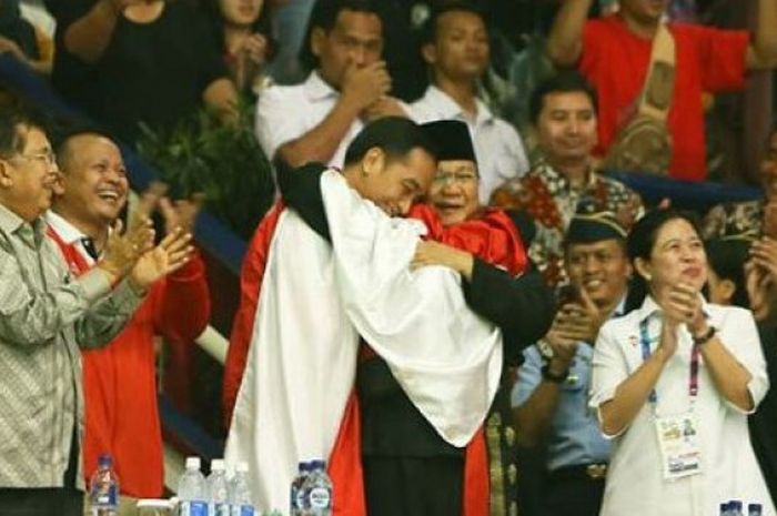 Momen saat pesilat Indonesia, Hanifan Yudha Kusumah, memeluk Joko Widodo dan Prabowo Subianto usai memastikan diri meraih medali emas pada cabor pencak silat Asian Games 2018, Rabu (29/8/2018).  