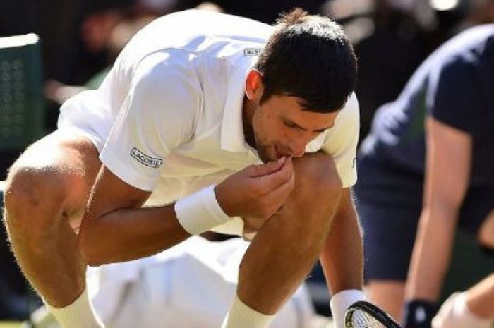 Petenis tunggal putra berkebangsaan Serbia, Novak Djokovic, melakukan selebrasi makan rumput usai memenangi Wimbledon 2018. 