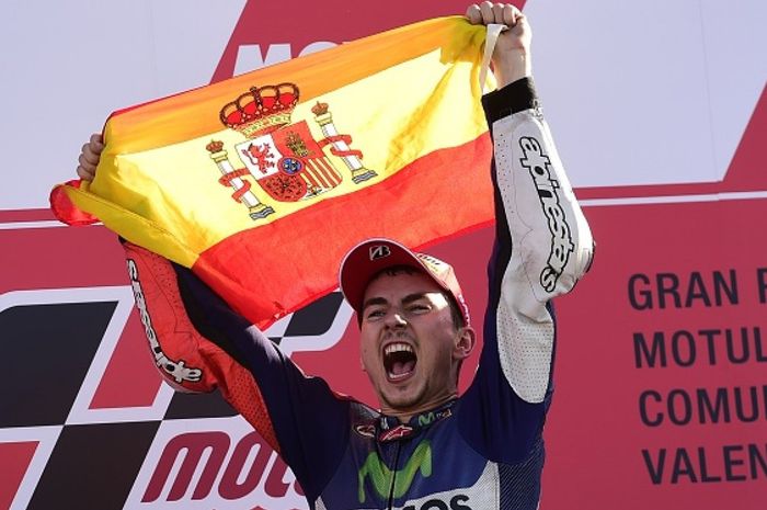 Pebalap Movistar Yamaha, Jorge Lorenzo, merayakan kemenangan di GP Valencia dengan mengibarkan bendera SPanyol di atas podium, Minggu (8/11/2015).