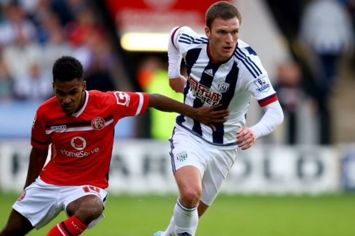 Bek Walsall, Rico Henry, berebut bola dengan Chris Brunt (West Brom) pada laga persahabatan di Walsall, 28 Juli 2015.