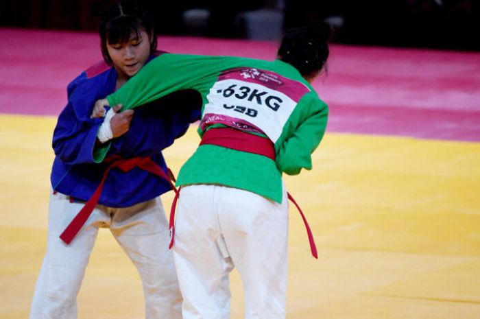 Atlet kurash Uzbekistan Dildor Shermetova (kiri) melakukan serangan terhadap atlet kurash Indonesia Khasani Najmu Shifa (kanan) saat bertanding pada babak Semifinal Kurash-63kg Asian Games 2018 di Assembly Hall JCC Senayan, Jakarta, Rabu (29/8). 