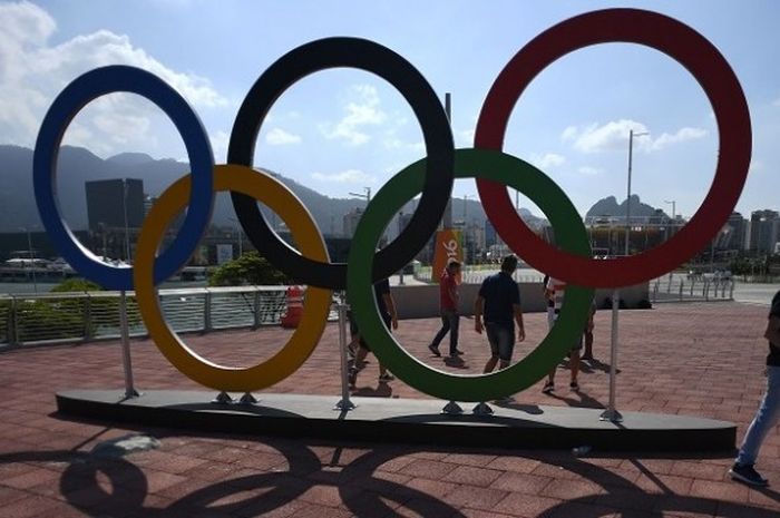 Seorang pengunjung sedang berjalan melintasi logo lima ring Olimpiade  di Olympic Park, Rio de Janeiro, Minggu (31/7/2016).