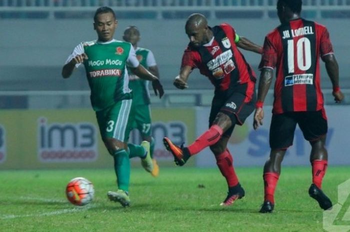 Penyerang Persipura, Boaz Solossa menendang bola di depan pemain PS TNI, Wiganda Pradika di Stadion Pakansari, Cibinong, Kabupaten Bogor,  Minggu (19/6/2016) malam.