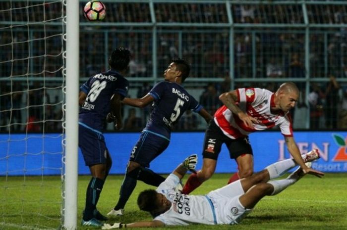 Kiper Arema FC, Kurnia Meiga (bawah), terjatuh setelah berduel dengan pemain Madura United di Stadion Kanjuruhan, Kabupaten Malang, pada Minggu (14/5/2017) malam