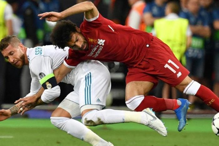 Striker Liverpool, Mohamed Salah (kanan), kehilangan keseimbangan saat dijaga ketat oleh bek Real Madrid, Sergio Ramos, dalam laga final Liga Champions di Stadion NSC Olimpiyskiy, Kiev, Ukraina pada 26 Mei 2018.