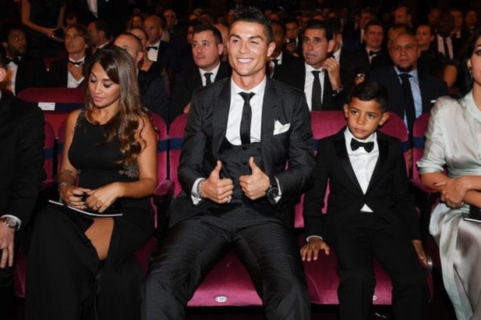 Cristiano Ronaldo tampak puas dengan mengacungkan dua jempol saat duduk di antara istri Lionel Messi, Antonella Rocuzzo, dan kekasihnya, Georgina Rodriguez dalam ajang The Best FIFA Football Awards 2017 , Selasa (24/10/2017) dini hari WIB, di London, Inggris.
