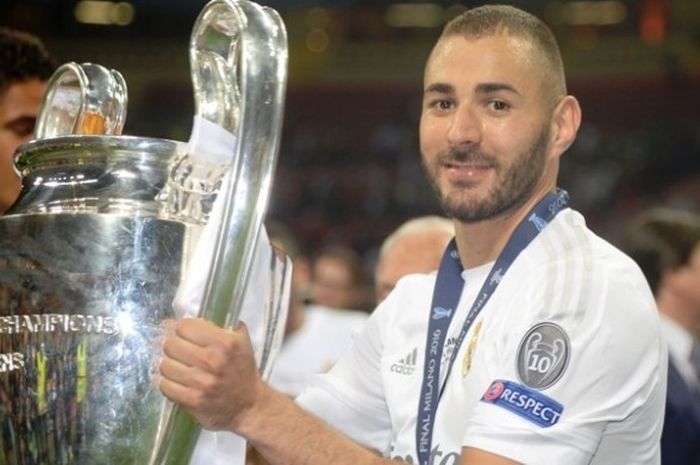 Penyerang Real Madrid, Karim Benzema, berpose dengan trofi seusai El Real menjuarai Liga Champions, Sabtu (28/5/2016). 