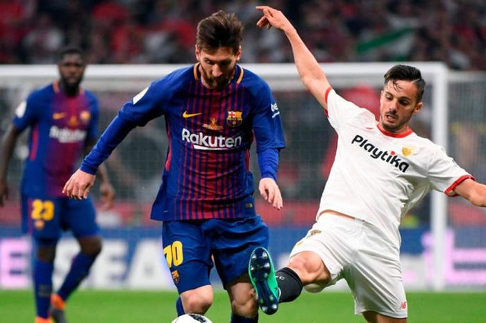 Barcelona Lionel Messi (kiri) bersaing dengan gelandang Sevilla, Pablo Sarabia, pada final Copa del Rey di stadion Wanda Metropolitano, Madrid, Minggu (22/4/2018) 