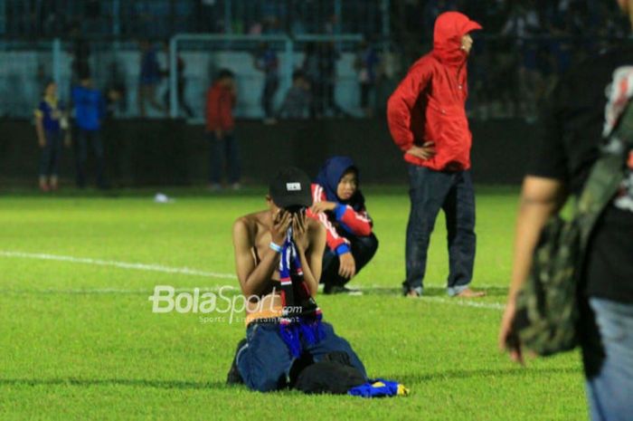 Seorang penonton tertunduk di lapangan Stadion Kanjuruhan setelah terkena gas air mata seusai pertandingan Liga 1 2018, Arema FC Vs Persib Bandung, Minggu (15/4/2018)