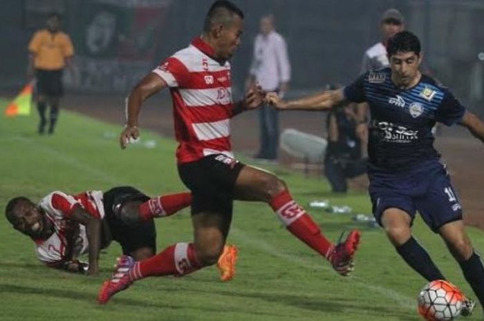 Dua pemain Madura United, Engel Berd Sani (terjatuh) dan Muhnar saat mencoba menghentikan gelandang Arema, Esteban Vizcarra di Stadion Gelora Bangkalan, Jumat (6/5/2016) malam.