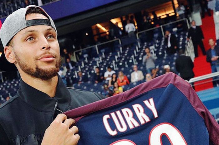 Point guard Golden State Warrior, Stephen Curry, memamerkan jersey tim Paris Saint-Germain yang dicetak dengan namanya dalam kunjungannya ke stadion kandang Paris Saint-German, Stadion Parc des Princes, Paris, (25/8/2017)